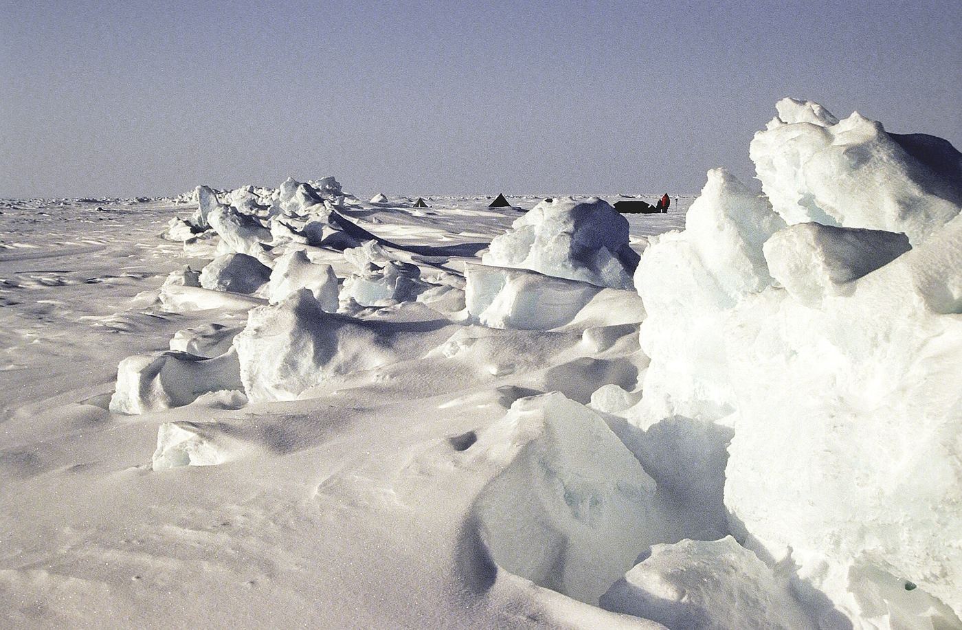 Aerial view of fractured arctic sea ice floating on dark ocean water with melt pools.